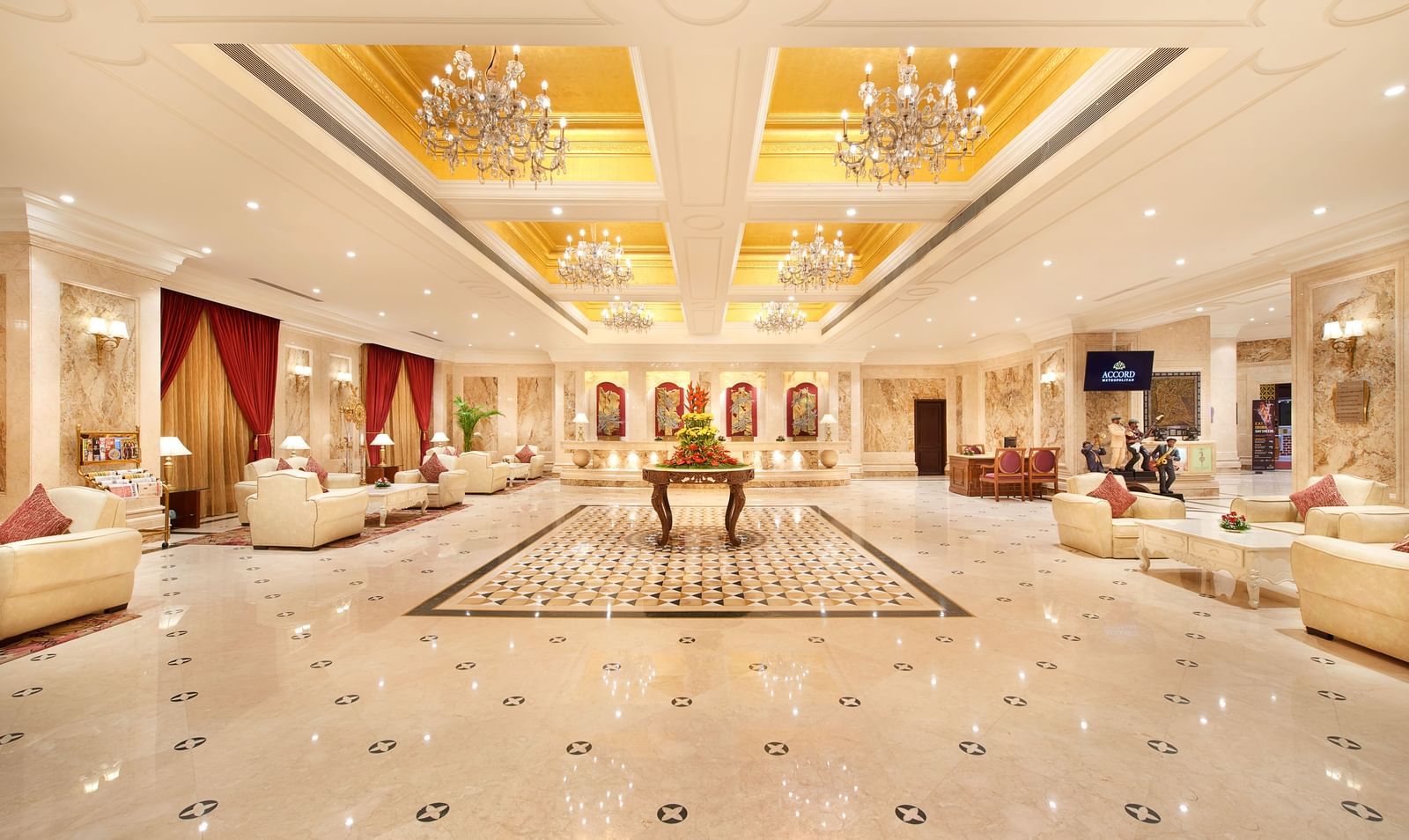 Spacious lobby at Accord Hotels and Resorts with luxurious interiors, wooden tables, cushioned furniture, chandeliers, and warm lighting.